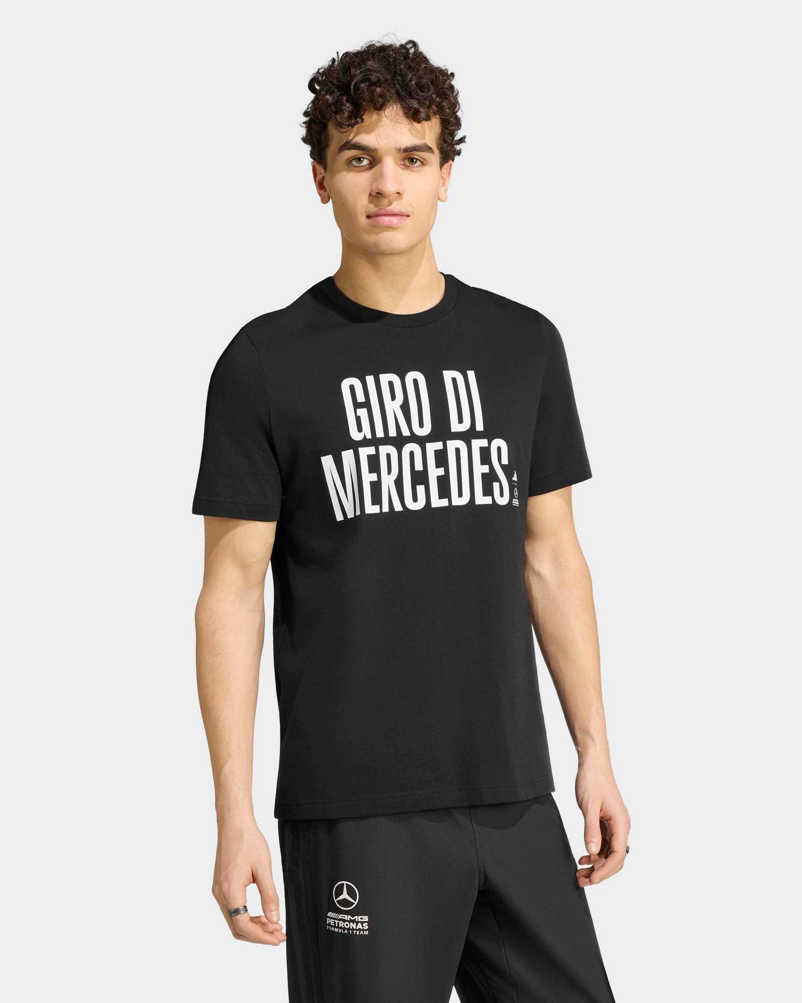 A male model wearing the black Mercedes Giro Di Mercedes graphic t-shirt featuring bold white typography.